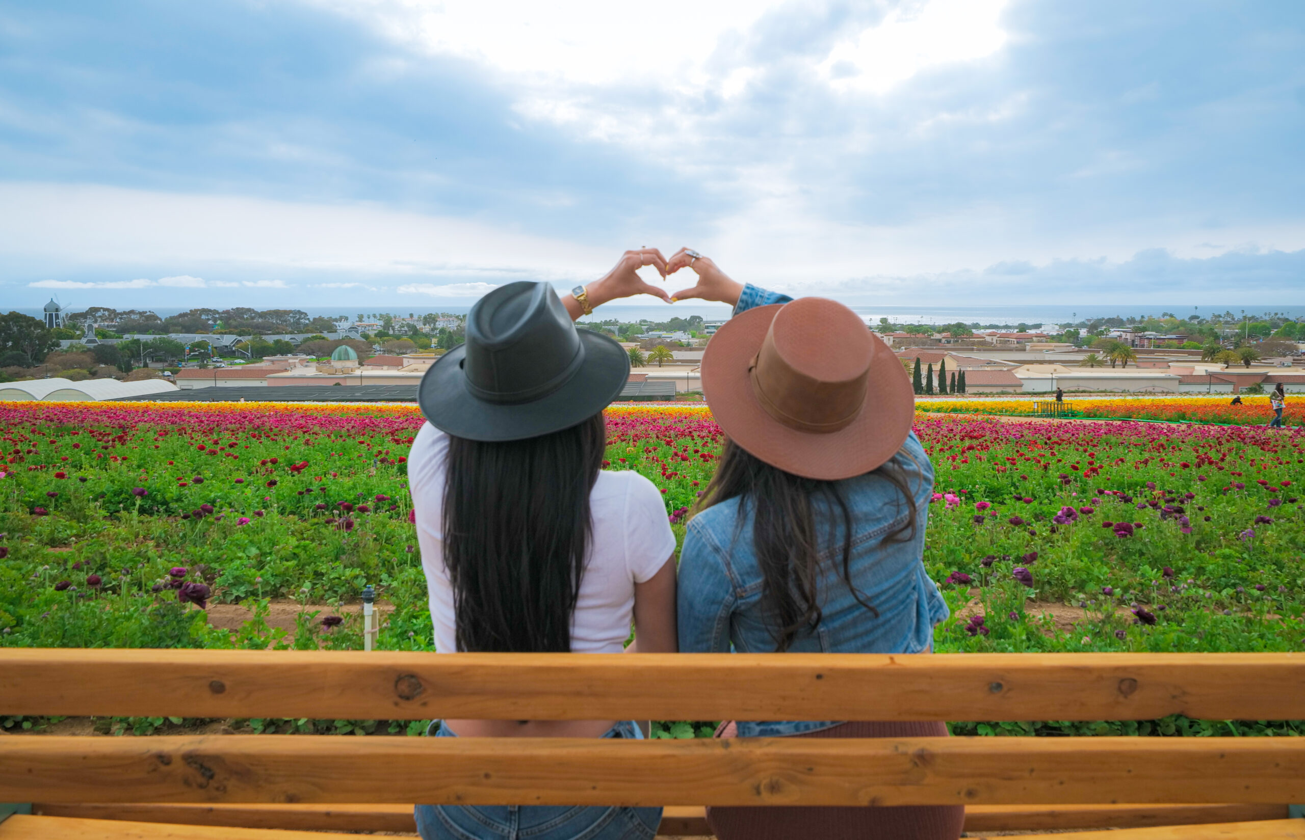 Friends sitting and making a heart with their hands at the Flower Fields Carlsbad