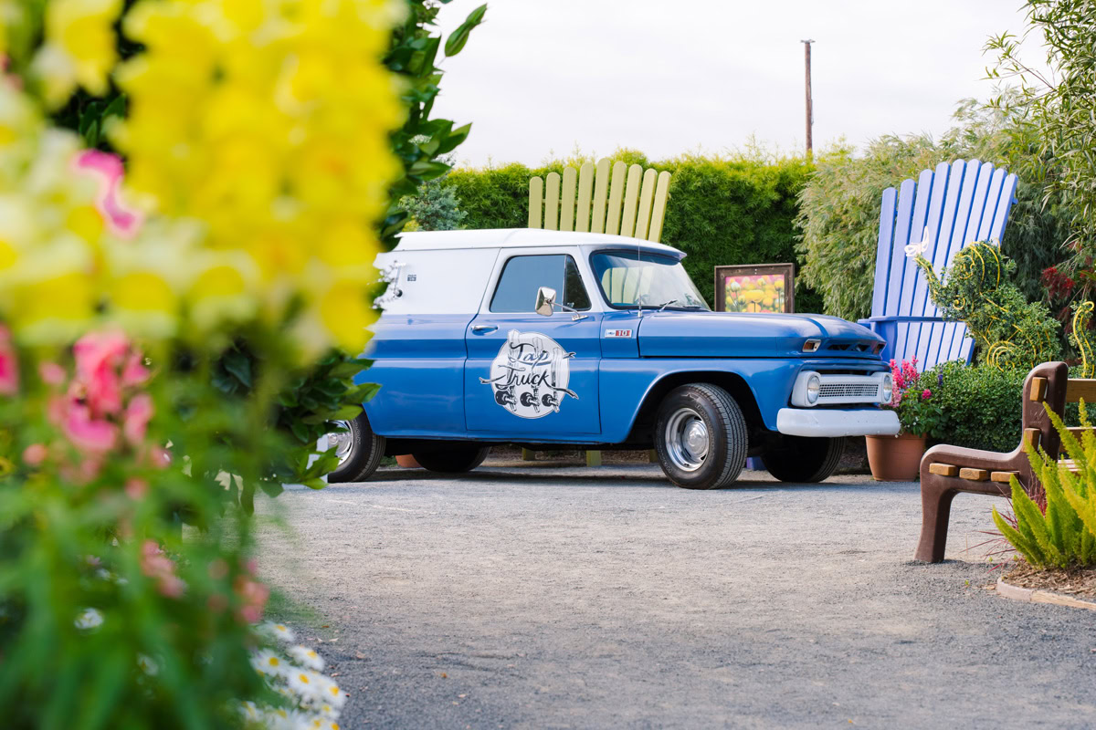Blue classic car in the background with two large decorative chairs at The Flower Fields Carlsbad.